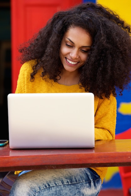 Smiling black woman using laptop at cafe