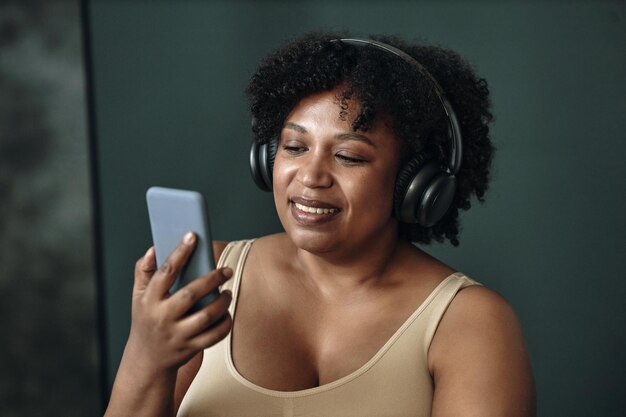 スマートフォンを使ってヘッドフォンをかぶった笑顔の黒人女性