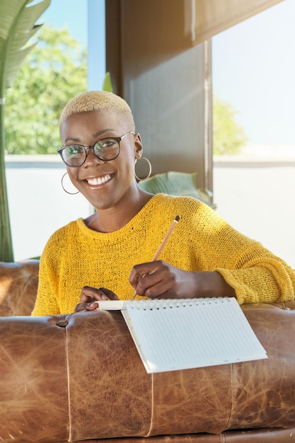 Smiling black woman writing in planner at home