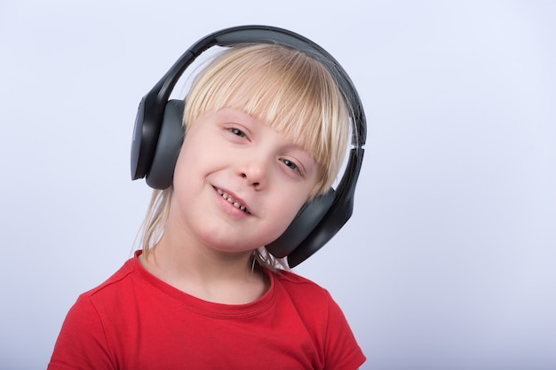 Smiling blond boy in headphones listen the music. Home studying.