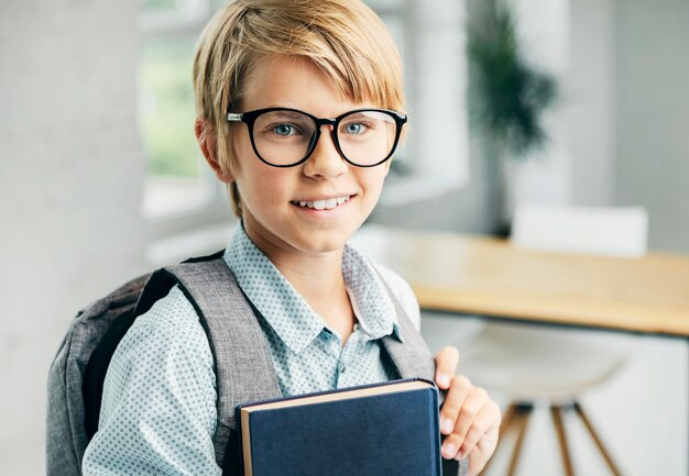 写真 教室で本を持っている笑顔の金髪の少年