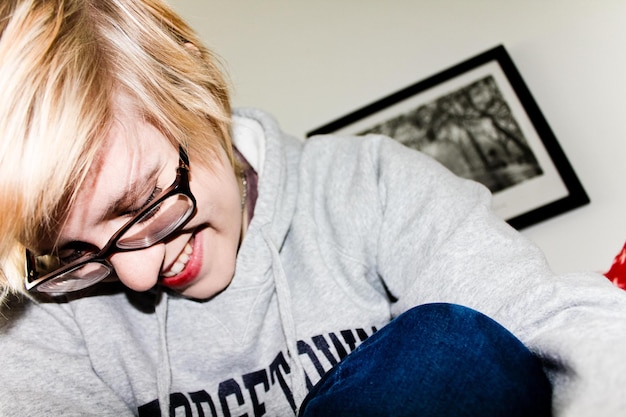 Photo smiling blond woman in eyeglasses sitting at home
