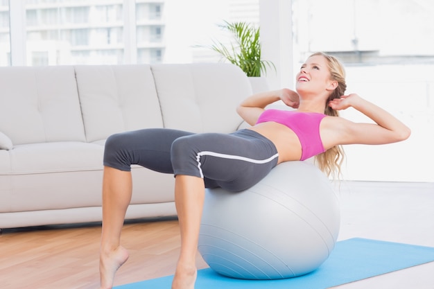 Smiling blonde doing sit ups with exercise ball