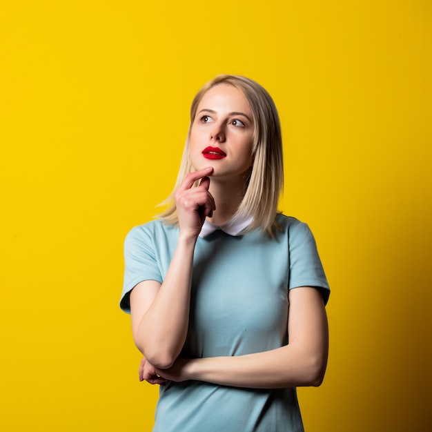 Smiling blonde girl in blue dress on yellow space