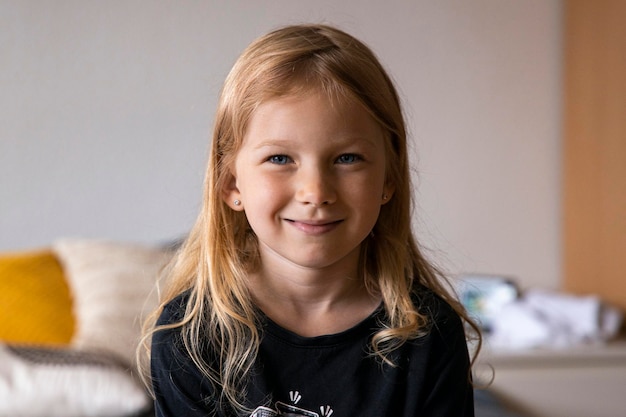 Smiling blonde girl child sitting on the sofa in the room