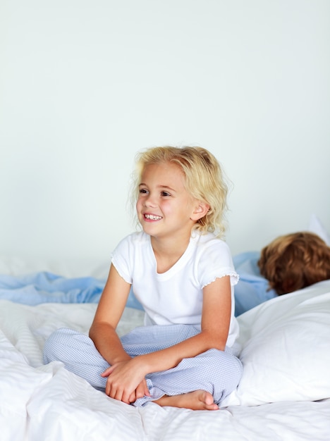 Smiling blonde girl sitting on a bed