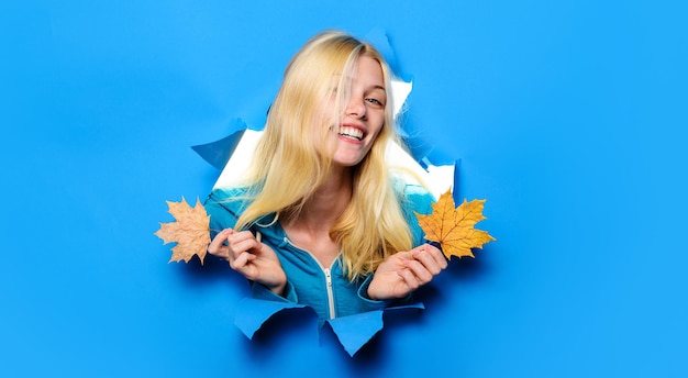 Smiling blonde girl with maple leaves looking through hole autumn sales discount copy space