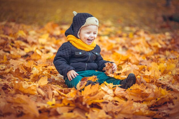 웃는 금발 아이는 자연에서 가을 잎을 들고 가을 아이는 가을에 잎이 떨어지는 귀여운 아이입니다.