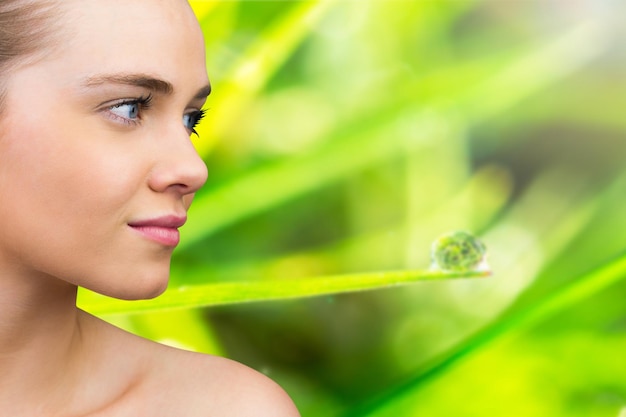 Photo smiling blonde natural beauty against dew on the green grass