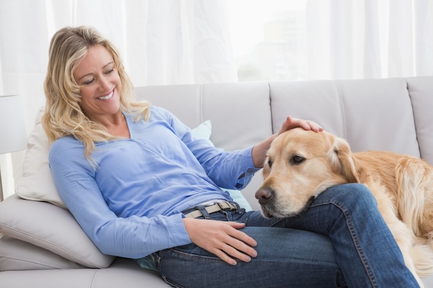 Smiling blonde woman petting her golden retriever 