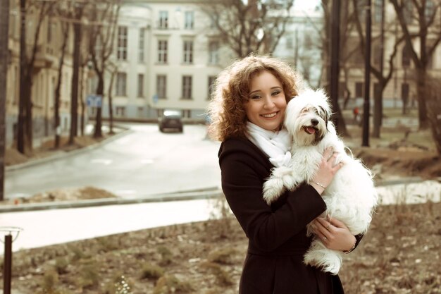 Smiling blonde  woman playing with dog  in the street