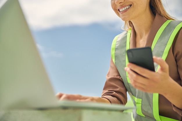 smiling blonde woman in a reflective vest sitting at her laptop