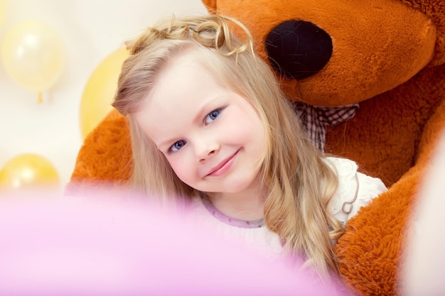 Smiling blueeyed girl posing with teddy bear