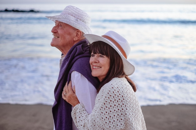 Smiling bonding senior couple embrace at the beach enjoying vacation and retirement