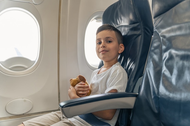 窓際の座席に座っている飛行機の中で笑顔の少年