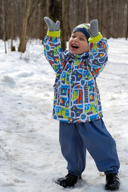 雪に覆われた森の背景に笑顔の少年。