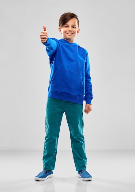 smiling boy in blue hoodie showing thumbs up