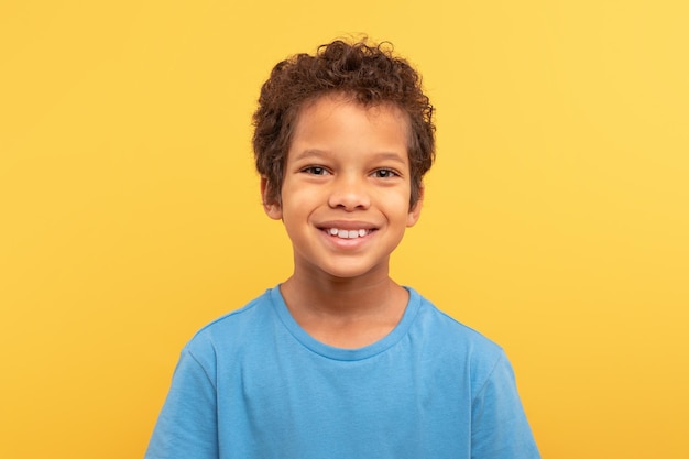 Smiling boy in blue tshirt against yellow backdrop