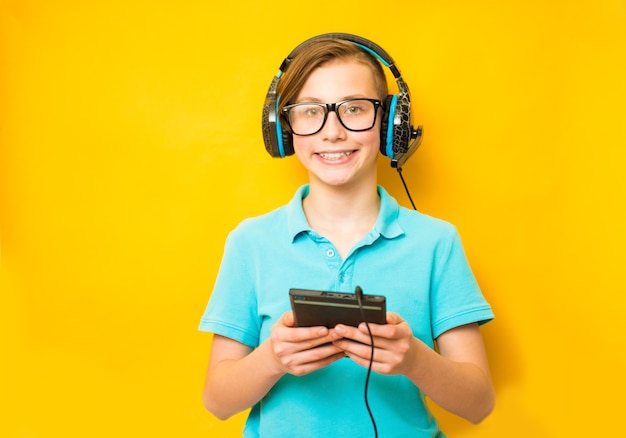 Smiling boy does his homework in headphones and with a tablet