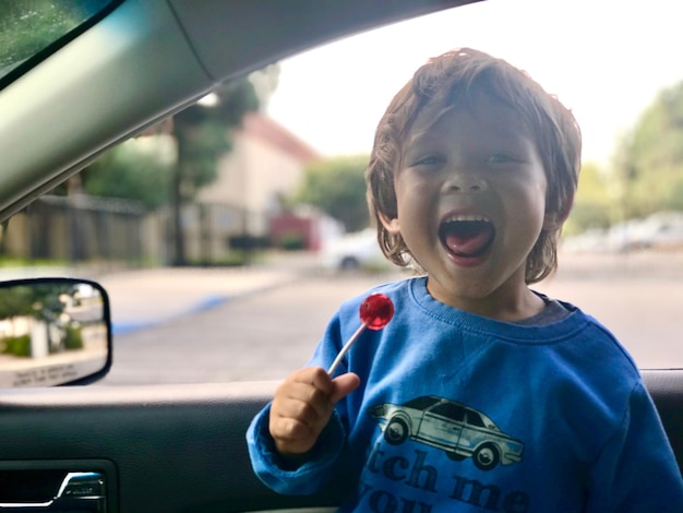 Photo smiling boy eating candy in car