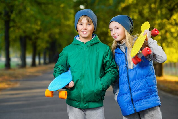 男の子と女の子のペニーボードを保持笑みを浮かべてください。