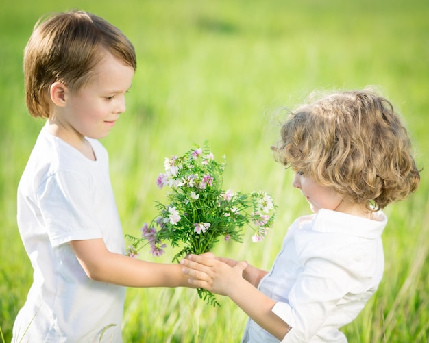 幸せな女の子に春の花の花束を与える笑顔の男の子