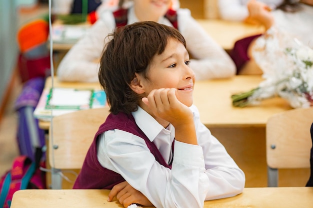 교실 에 앉아 있는 웃는 소년 이 눈 을 돌리고 있다