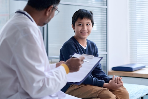 Photo smiling boy looking at doctor