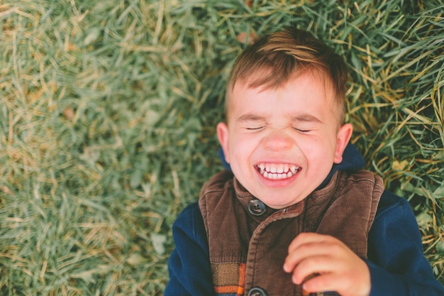 Photo smiling boy lying down on field