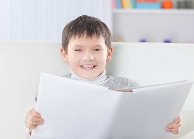 Smiling boy reading a book in the nursery