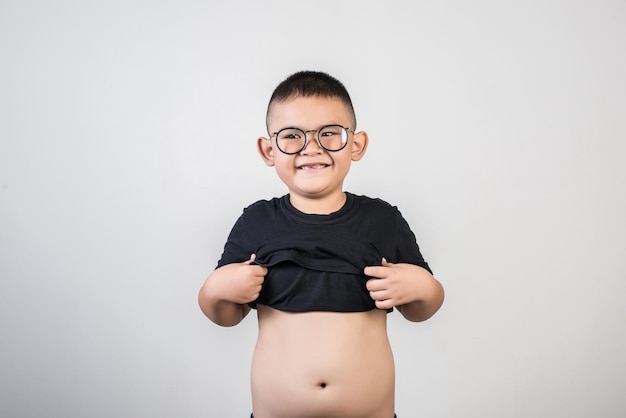 Photo smiling boy showing abdomen while standing against gray background