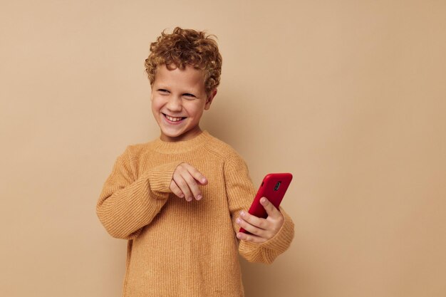 Smiling boy in a sweater with a phone in his hands communication