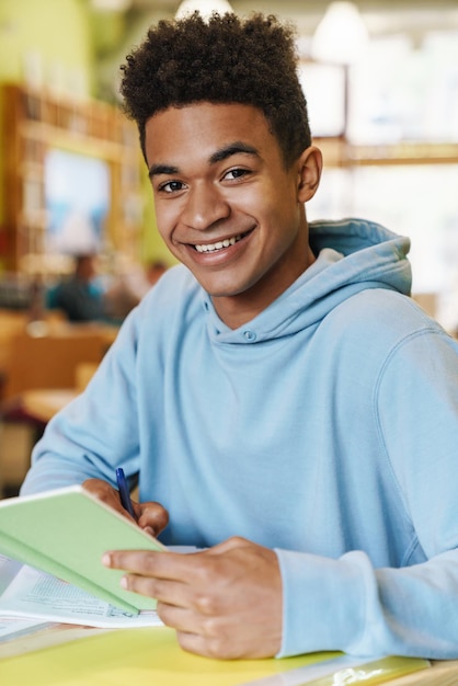 Foto adolescente sorridente che studia mentre è seduto al mozzo al chiuso