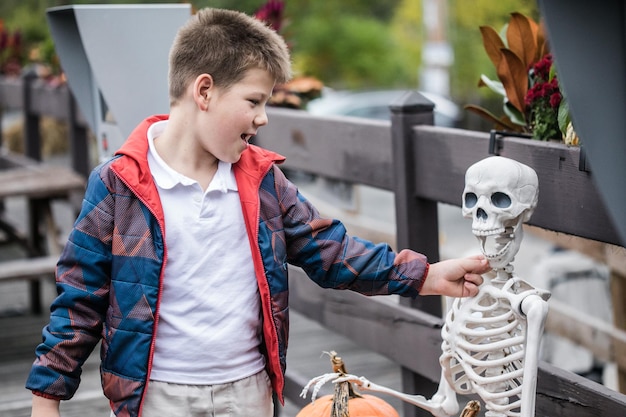 Smiling boy touching teeth you skeleton during Halloween teeth