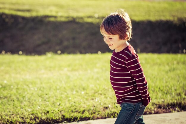 Фото Улыбающийся мальчик идет по земле в парке