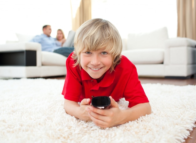 Smiling boy watching TV lying on the floor 