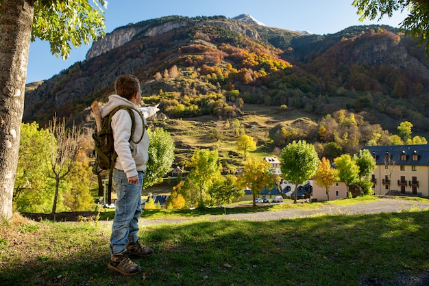 Foto ragazzo sorridente con lo zaino in montagne di autunno