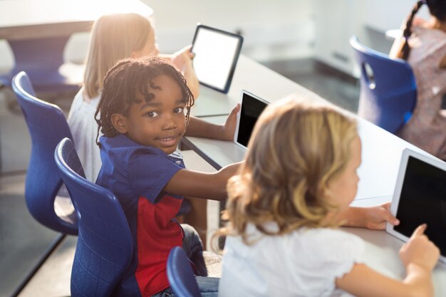 Smiling boy with classmates using digital tablet