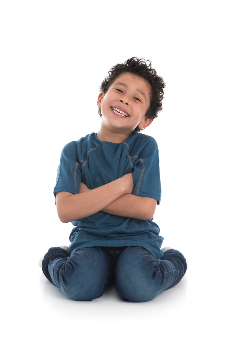 Photo smiling boy with crossed arms sitting on the ground