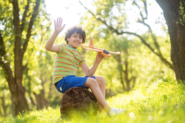 Photo smiling boy with toy airplane in park