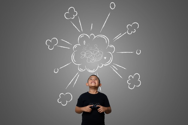 Photo smiling boy with video game looking up while standing against gray background