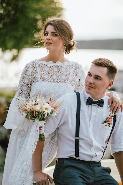 Sorridente sposa bruna giovane donna con il bouquet stile boho con lo sposo