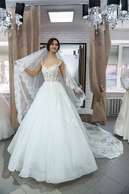 Smiling bride fitting dress in wedding salon