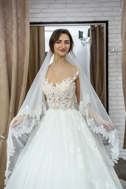結婚式のサロンで花嫁のフィッティングドレスを笑顔