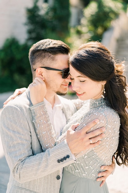 Smiling bride and groom hugging touching foreheads