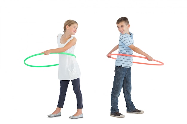 Photo smiling brother and sister playing with hula hoop
