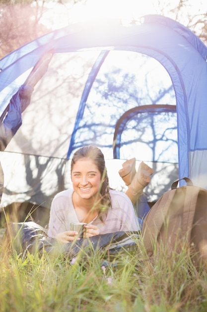 Foto campeggiatore castana sorridente che si trova in tenda