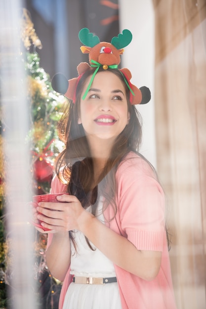 Smiling brunette in christmas hat holding mug