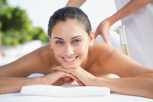 Smiling brunette enjoying a massage poolside