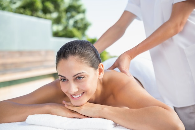 Smiling brunette enjoying a massage poolside